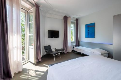 Schlafzimmer mit einem Bett, einem Stuhl und Fenstern in der Unterkunft Continental Park in Luzern