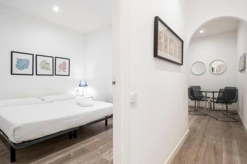 a white bedroom with a bed and a table at Two bedroom flat in PobleNou in Barcelona