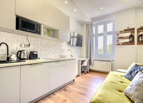 kuchnia z białymi szafkami i kanapą w pokoju w obiekcie Studio Mini Apart 6.2 - ACCO RENT w Gdańsku