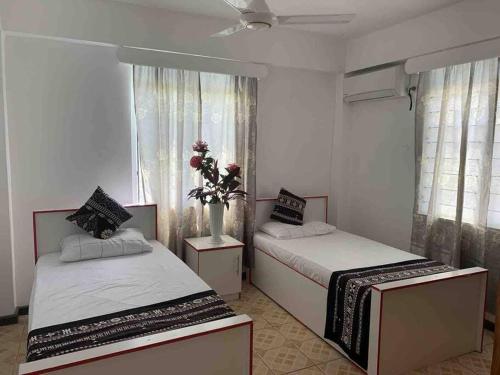 1 dormitorio con 2 camas y un jarrón con flores en Modern with class near Airport en Nadi