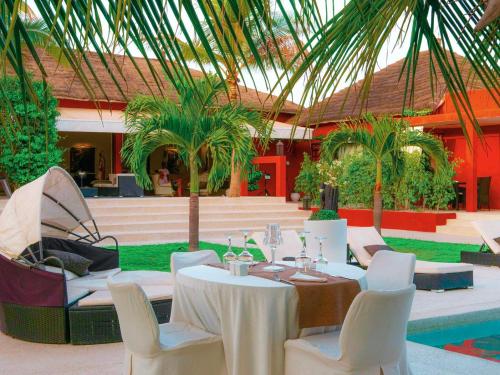 a table and chairs in a courtyard with a pool at Villa Le Petit Paradis Saly Boutique Hotel in Ngaparou