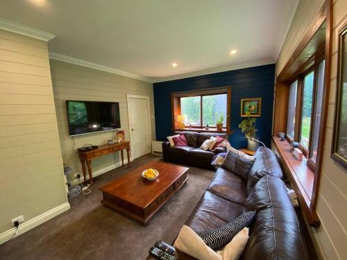 a living room with a leather couch and a table at The Barn, Bowral in Bowral