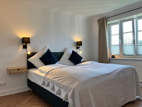 Kapitänshaus Hamburg Altes Land في هامبورغ: غرفة نوم بسرير ذو شراشف بيضاء ومخدات زرقاء