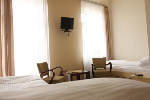 a hotel room with a bed and two chairs and a tv at Stara Poczta in Zambrów