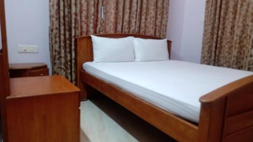 Dormitorio pequeño con cama y mesa en Atlas Home Stay, en Kodanad
