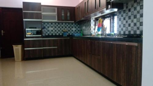 cocina con armarios de madera y encimera negra en Atlas Home Stay, en Kodanad
