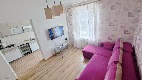 a living room with a purple couch and a kitchen at Sakņu 16/18 in Daugavpils