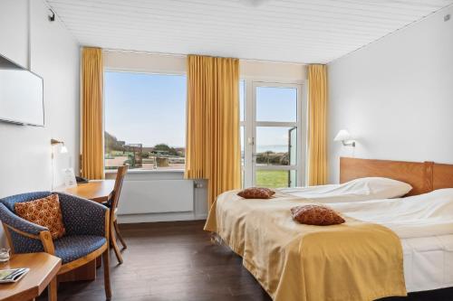 a hotel room with two beds and a desk and a window at Hotel Pinenhus in Glyngøre