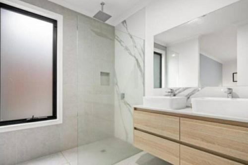 een witte badkamer met 2 wastafels en een raam bij Cheerful 3 bedroom home with parking 