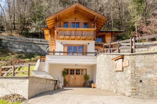 a log home with a stone wall at B&B Chalet Il Picchio in Varzo