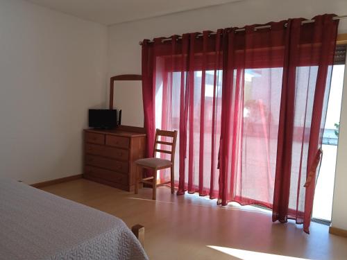 a bedroom with a bed and a dresser and a window at O Galito in Praia de Mira