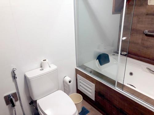 a bathroom with a toilet and a shower and a sink at Center Suiço Flats in Campos do Jordão