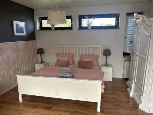 um quarto com uma grande cama branca com almofadas cor-de-rosa em Gemütliche Heide-Ferienwohnung em Soltau
