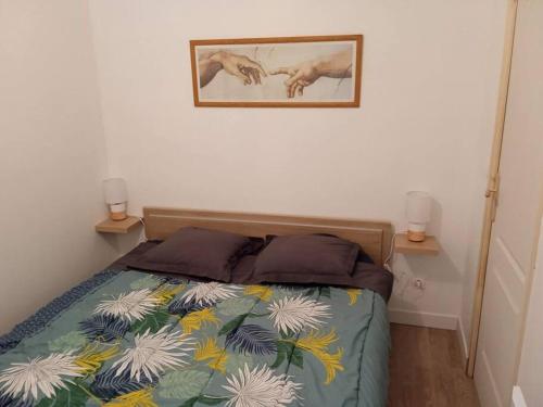 a bedroom with a bed and two lamps on the wall at Petit logement avec entrée indépendante 