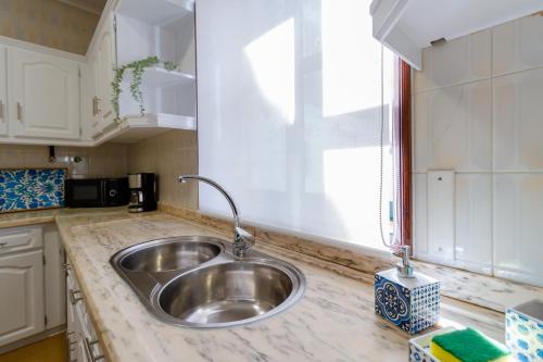 a kitchen counter with a sink and a window at Apartment close to the Ria de Aveiro, São Jacinto in Aveiro