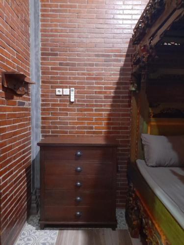 1 dormitorio con tocador de madera y pared de ladrillo en Krobyongan staycation kalaras, en Karanganyar