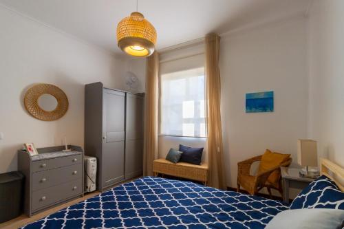 a bedroom with a blue bed and a window at Apartment close to the Ria de Aveiro, São Jacinto in Aveiro