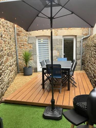 une terrasse en bois avec une table, des chaises et un parasol dans l'établissement Duplex 6/8p centre Plouha, à Plouha