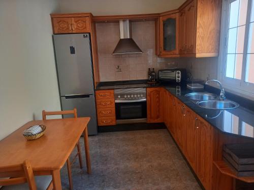 uma cozinha com armários de madeira e um frigorífico de aço inoxidável em Casa Islas 1 em Ingenio