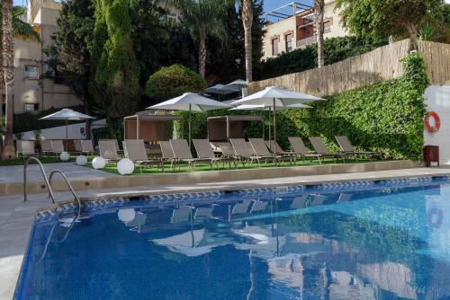 a swimming pool with chairs and umbrellas at Hotel Costa Málaga - Adults Recommended - by Pierre & Vacances in Torremolinos