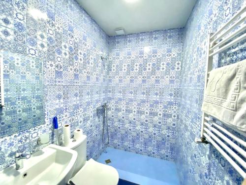 a blue tiled bathroom with a toilet and a sink at Freeze Inn Mestia in Mestia