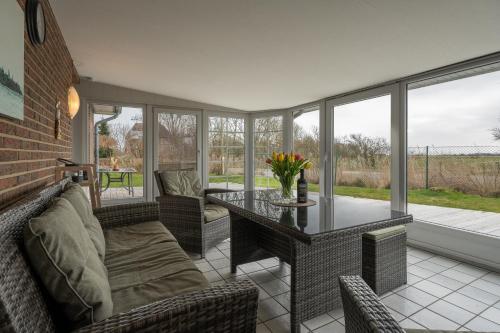 une véranda avec une table et des chaises dans l'établissement Ferienwohnungen Haus Schau ins Land nah an der Nordsee, à Emmelsbüll-Horsbüll