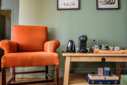 an orange chair sitting next to a wooden table at The Globe Inn in Wells next the Sea