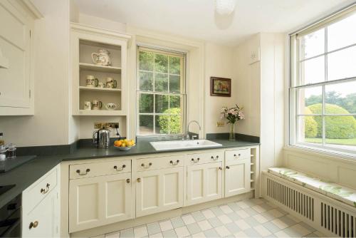 uma cozinha com armários brancos, um lavatório e uma janela em Bell Flat in Broughton Hall em Skipton