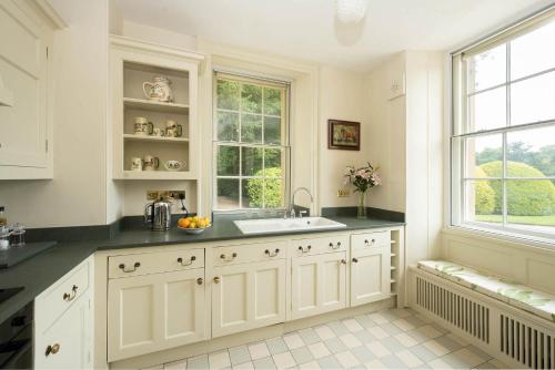 a kitchen with white cabinets and a sink and a window at Bell Flat in Broughton Hall in Skipton
