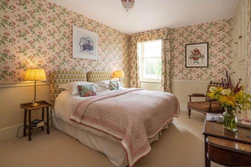 um quarto com uma cama com papel de parede floral cor-de-rosa em Bell Flat in Broughton Hall em Skipton