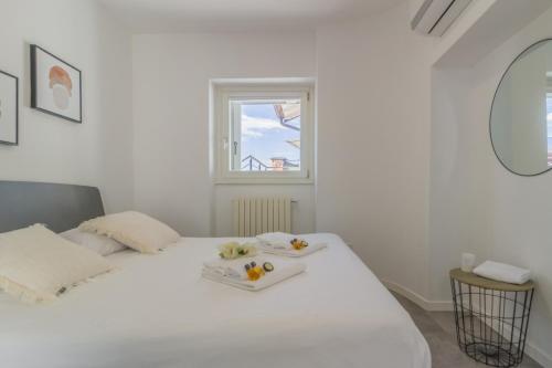 a white bedroom with a white bed with two trays on it at La terrazza di Marta in Varenna