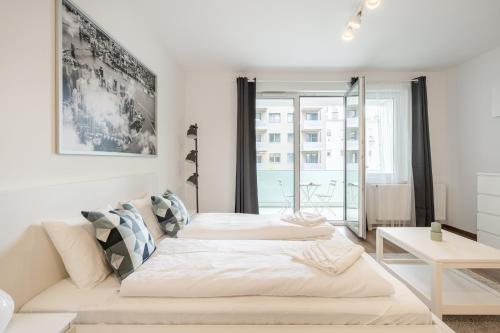 White Cottage Studio في بودابست: سريرين في غرفة بيضاء مع نافذة