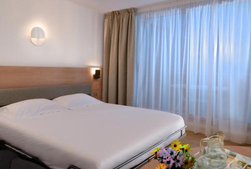 a bedroom with a white bed and a window at Residence Residéal Antibes in Antibes