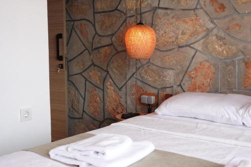a bedroom with a bed and a stone wall at Tomsan Suites & Villas Akyaka in Akyaka
