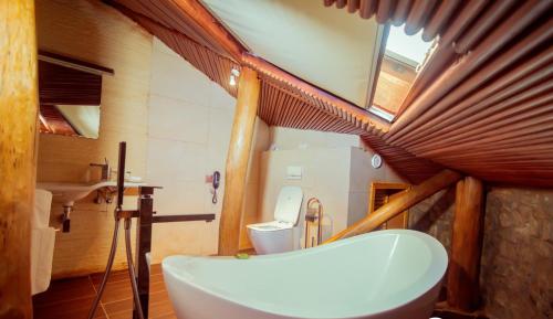 a bathroom with a tub and a toilet and a window at Trois Ore Residences & Green Earth Bistro in Ibadan
