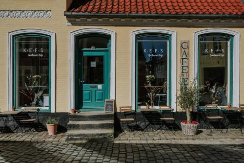 un bâtiment avec une porte bleue, des chaises et des tables dans l'établissement KEFS Guesthouse & Café, à Ærøskøbing