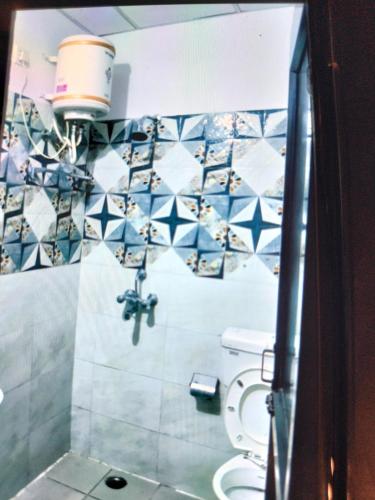 a bathroom with a toilet and blue and white tiles at Hotel Shiva Haridwar - nearby bus and railway station in Haridwār