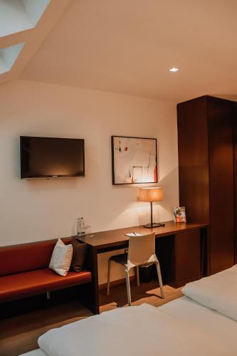 a bedroom with a desk and a bed with a lamp at Hotel Hofwirt Neubeuern in Neubeuern