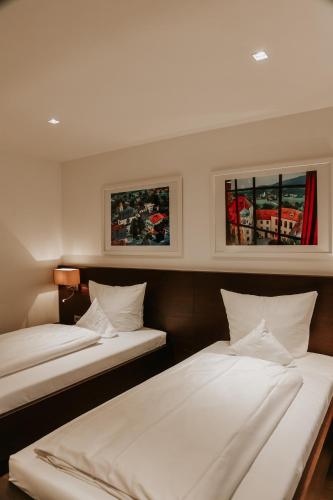 two beds in a room with two windows at Hotel Hofwirt Neubeuern in Neubeuern