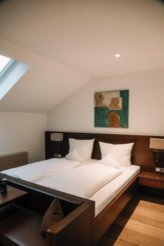 a bedroom with a large bed with white sheets at Hotel Hofwirt Neubeuern in Neubeuern