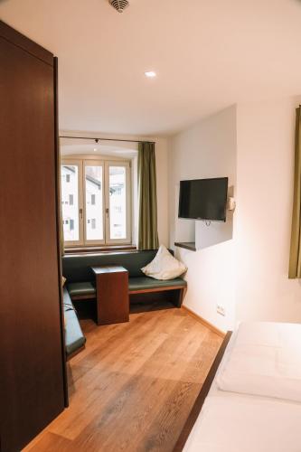 a hotel room with a couch and a television at Hotel Hofwirt Neubeuern in Neubeuern