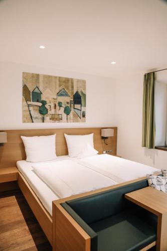 a bedroom with a large bed with white sheets at Hotel Hofwirt Neubeuern in Neubeuern