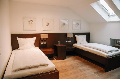 a bedroom with two beds and two lamps and a window at Hotel Hofwirt Neubeuern in Neubeuern