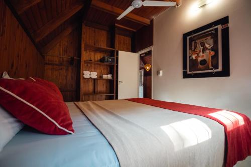 a bedroom with a large bed with red pillows at Palma Real Bungalow in Puerto Iguazú