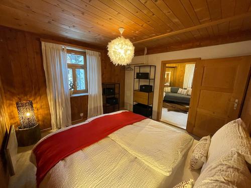 - une chambre avec un grand lit et un lustre dans l'établissement Ferienwohnung Canzlia Veglia, à Sedrun