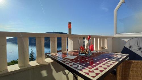 a table on a balcony with a view of the water at Jakopovic Apartments in Rogoznica