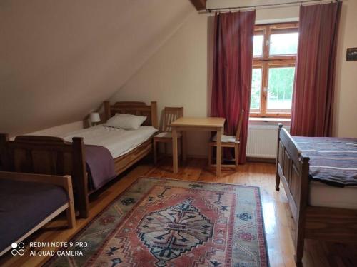 a bedroom with two beds and a table and a window at Komfortowy dom wakacyjny dla kilku rodzin 