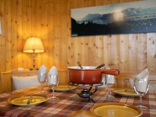 a table with a pot and plates and wine glasses at Apartment Muverans I L2 by Interhome in Nendaz