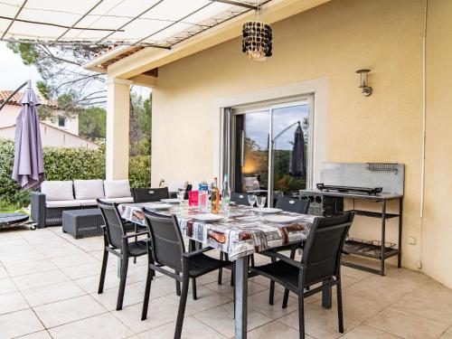 un patio con mesa, sillas y parrilla en Holiday Home Au Romarin - BEF130 by Interhome, en Bagnols-en-Forêt
