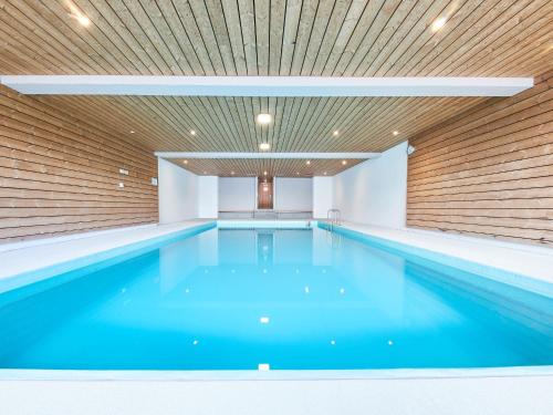 a swimming pool with blue water in a building at Studio Hameau D12 by Interhome in Les Collons